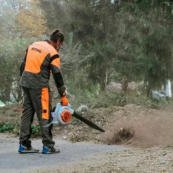 Воздуходувкой сдувают пыль и мусор с дороги